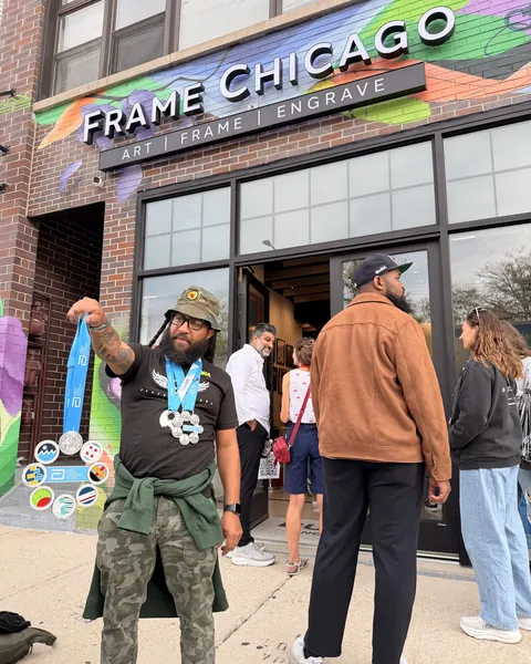 A runner outside Frame Chicago holding up his marathon medals.