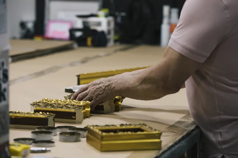 Gilded frames being finished by hand on the workbench.